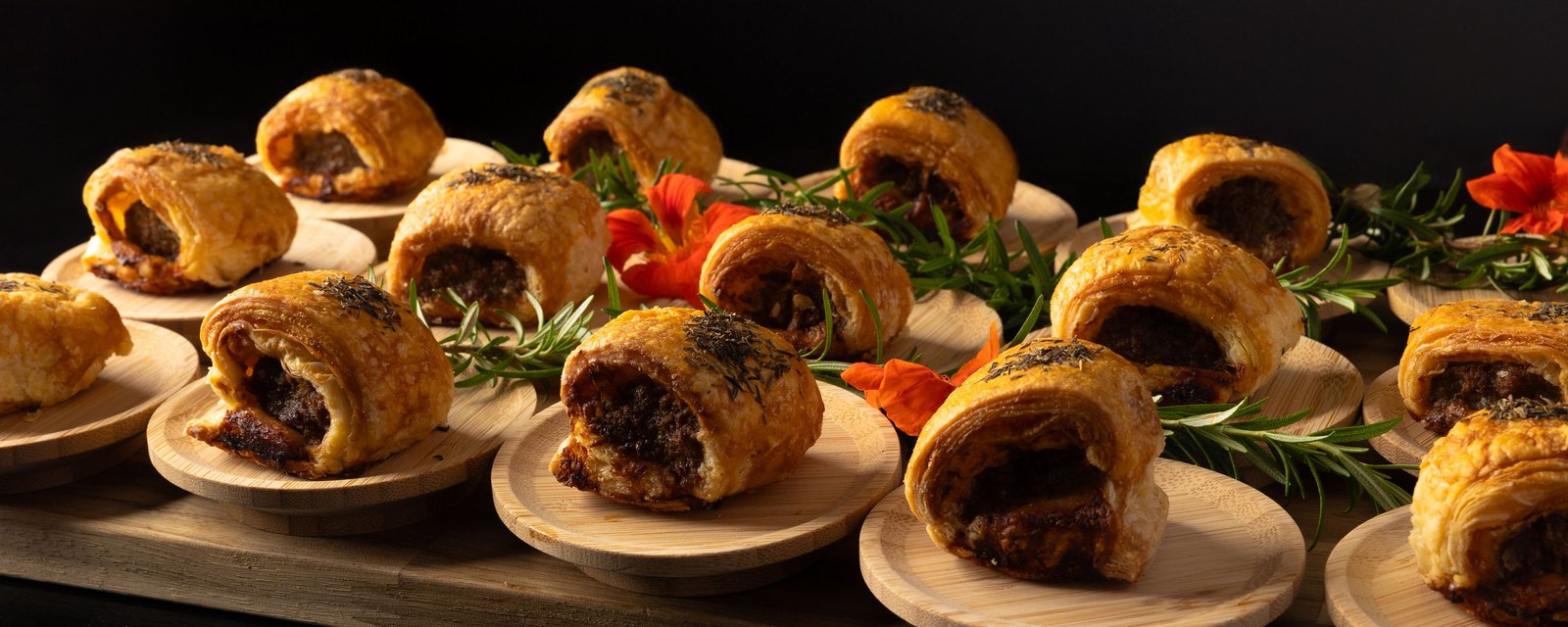 Beef sausage rolls plated individually on bamboo